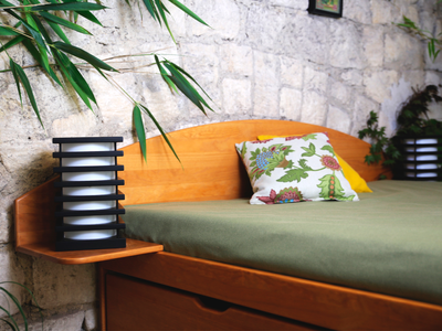 Tête de lit demi-lune Massako en bois clair avec tablettes de chevet intégrées, Lampe design noire et blanche posée.